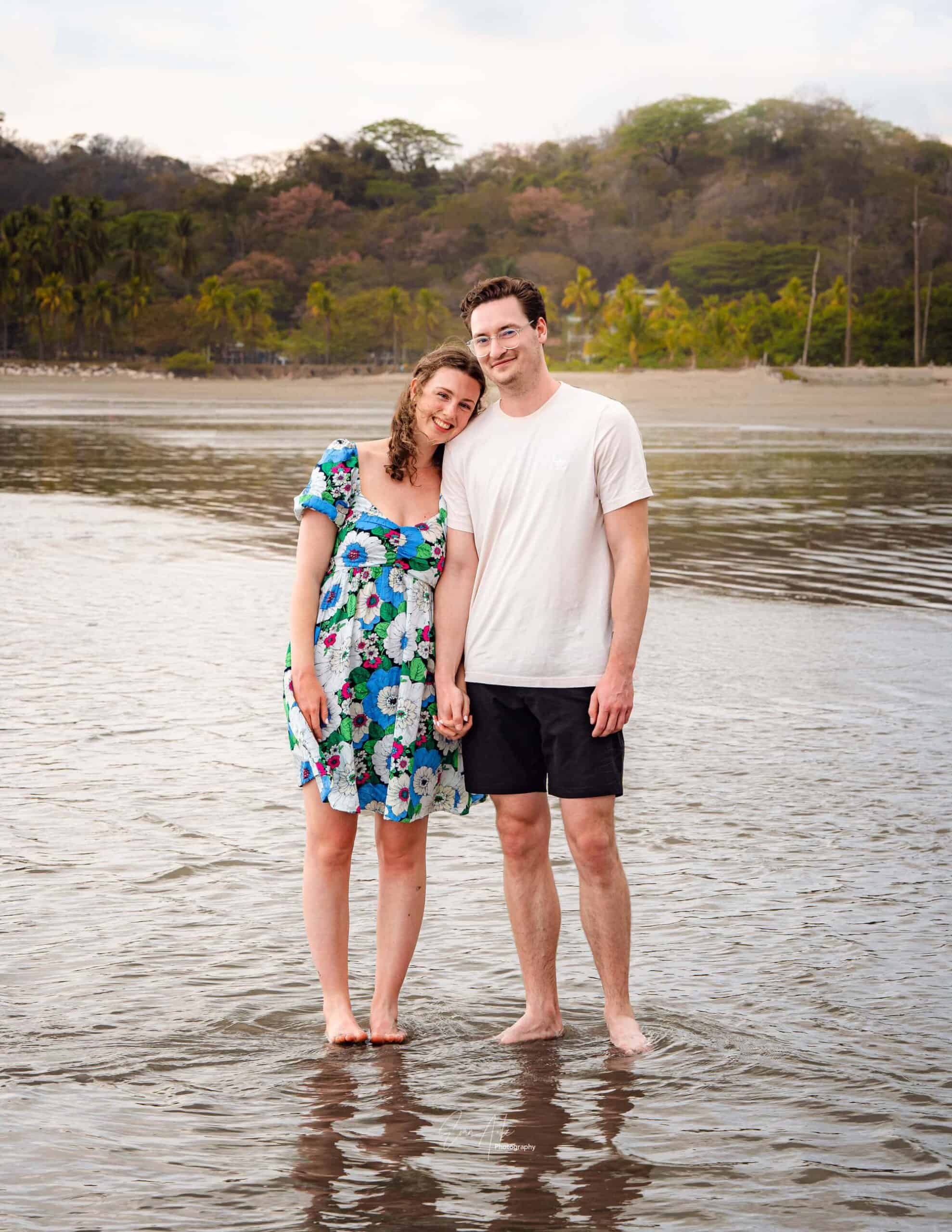 Samara Family Portrait Session 5 by Evan Aube Creative Happy couple standing in shallow water at the beach, smiling and holding hands.
